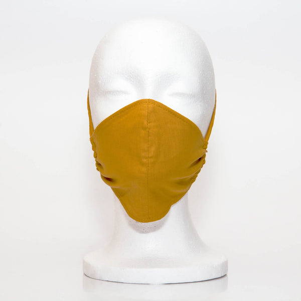 Mustard Alpha Mask Front View: Solid mustard colour fabric face mask contoured to fit comfortably on your face. This is a 3 layer fabric mask with a middle pocket to insert the filter as the third layer. The bias binding straps is easily adjustable for your comfort and ties behind your head. This mask has a removable filter. This mask an unisex adult fit.