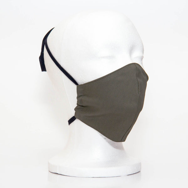 Olive Alpha Mask Side View: Solid olive colour fabric face mask contoured to fit comfortably on your face. This is a 3 layer fabric mask with a middle pocket to insert the filter as the third layer. The bias binding straps is easily adjustable for your comfort and ties behind your head. This mask has a removable filter. This mask an unisex adult fit.