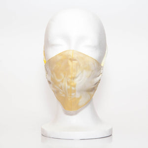 Yellow Tie-Dye Alpha Mask Front View: The turmeric and milk tie dye fabric face mask contoured to fit comfortably on your face. This is a 3 layer fabric mask with a middle pocket to insert the filter as the third layer. The bias binding straps is easily adjustable for your comfort and ties behind your head. This mask has a removable filter. This mask an unisex adult fit. The natural dye of turmeric was used to create this beautiful tie dye. The print may vary due to the nature of dying each mask by hand.
