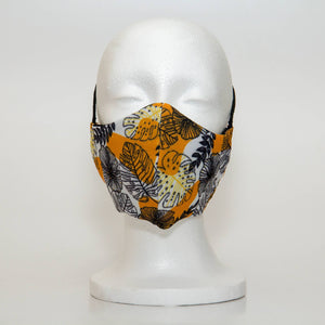 Oltre Print Mask Front View: Black outline floral with yellow shapes print. Abstract yellow shpaes and black outlined floral print transforms the essential mask to a fashion item. 3 Layer fabric mask with a middle filter layer that is contoured to fit comfortably on your face. Mask will fit women and teen girls.