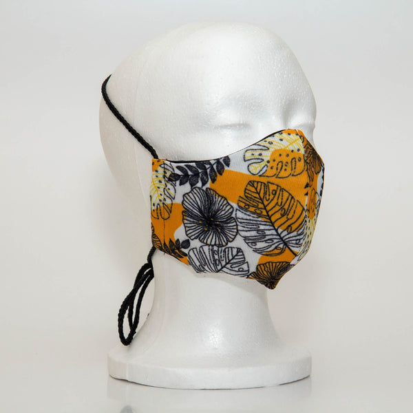 Oltre Print Mask Side View: Black outline floral with yellow shapes print. The soft woven strap is easily adjustable around your head for your comfort. 3 Layer fabric mask with a middle filter layer that is contoured to fit comfortably on your face. Mask will fit women and teen girls.