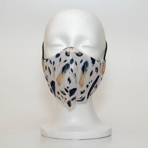 Oltre Print Mask Front View: Blue Feathers print. The beautiful, soft colour combination of navy and off-white brings this print to life. 3 Layer fabric mask with a middle filter layer that is contoured to fit comfortably on your face. Mask will fit women and teen girls.