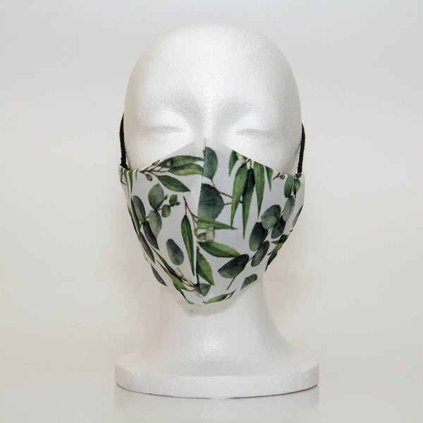 Oltre Print Mask Front View: Green leaves print. The natural and tranquil print of leaves is a eye-catching print that will complement your outfit. 3 Layer fabric mask with a middle filter layer that is contoured to fit comfortably on your face. Mask will fit women and teen girls.