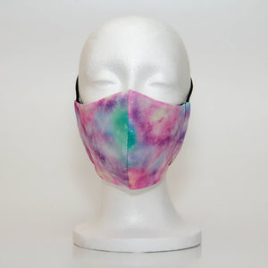 Oltre Print Mask Front View: Cotton Candy print. The abstract print of cloudy pink, blue and purple is fun and sweet like cotton candy. 3 Layer fabric mask with a middle filter layer that is contoured to fit comfortably on your face. Mask will fit women and teen girls.