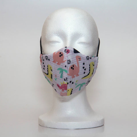 Oltre Print Mask Front View: Dinasaurs print. Our whimsical Dinasaur print is adorably cute and fun. 3 Layer fabric mask with a middle filter layer that is contoured to fit comfortably on your face. Mask will fit pre school girls between 3 to 6 years old.