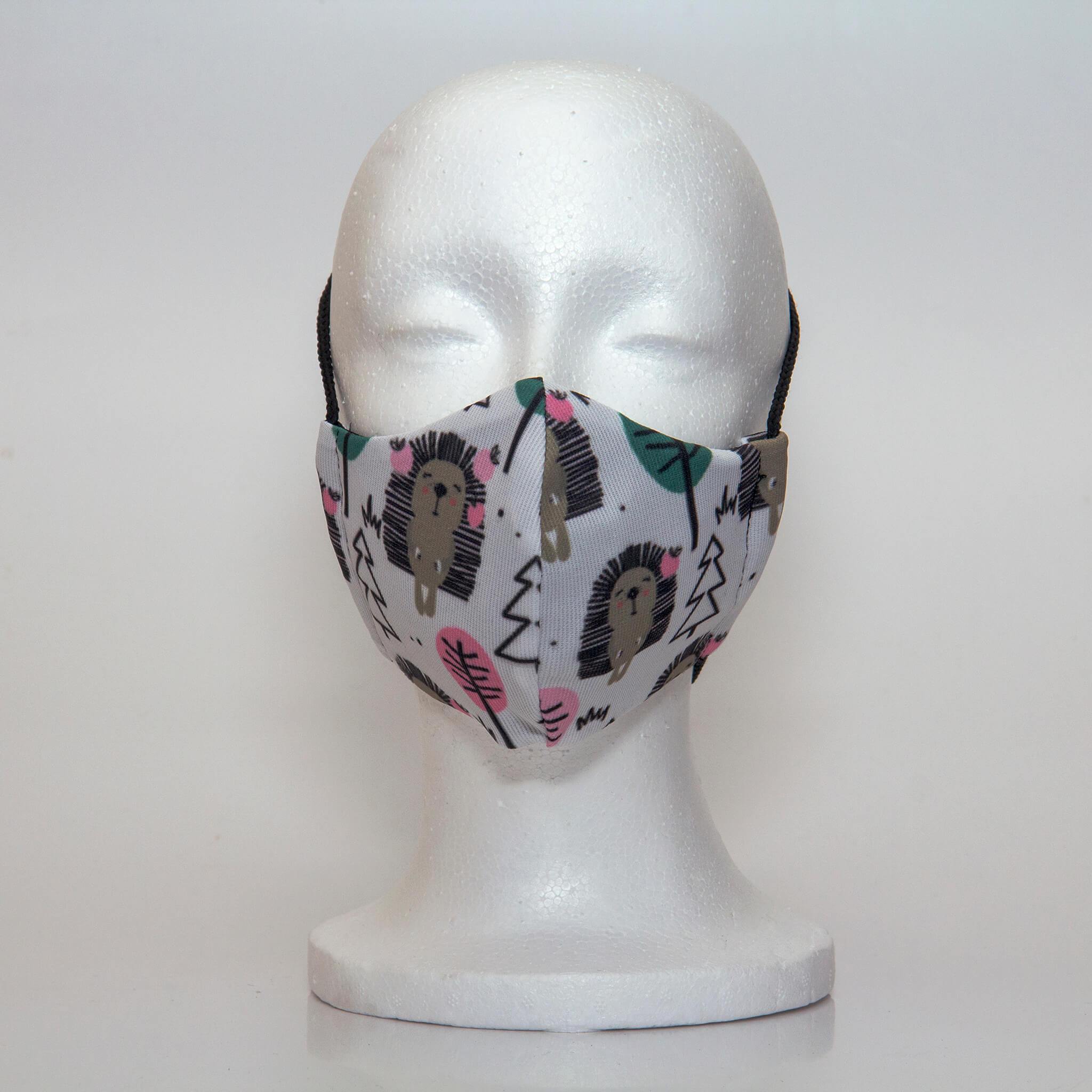 Oltre Print Mask Front View: Hedgehogs print. The hedgehog print is our playful interpretation of this cute animal for a girly design. 3 Layer fabric mask with a middle filter layer that is contoured to fit comfortably on your face. Mask will fit pre-teen girls between 7 to 12 years old.