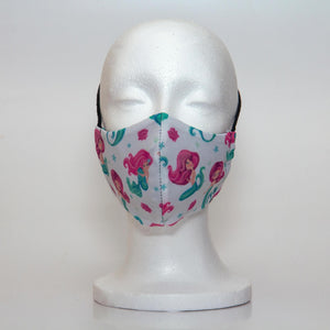 Oltre Print Mask Front View: Mermaids print. The beautiful mermaid print is a pretty interpretation for all the little mermaid fans. 3 Layer fabric mask with a middle filter layer that is contoured to fit comfortably on your face. Mask will fit pre-teen girls between 7 to 12 years old.