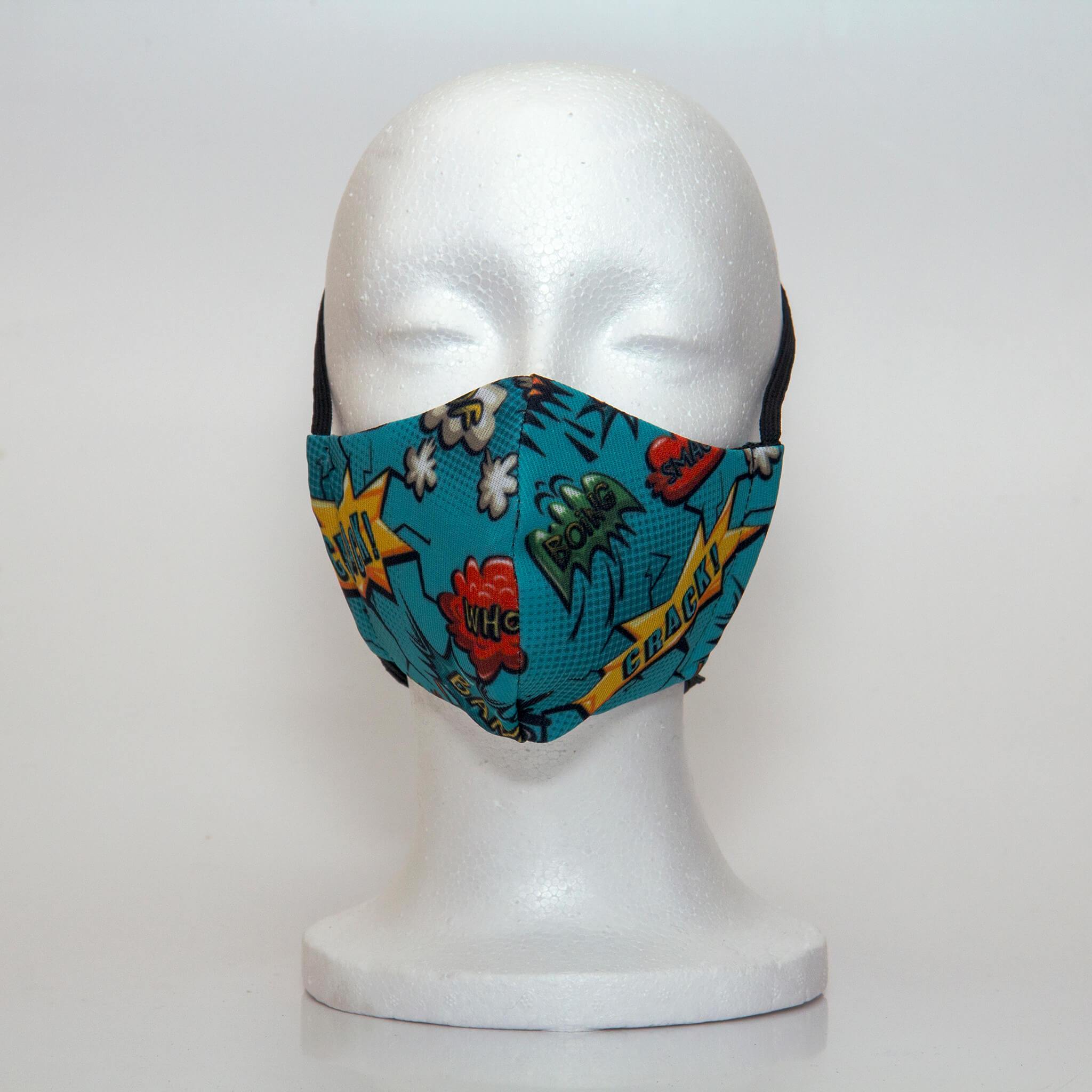Oltre Print Mask Front View: Comics Blue print. Our Fun comics blue print for the comic book lover. 3 Layer fabric mask with a middle filter layer that is contoured to fit comfortably on your face. Mask will fit pre-teen boys between 7 to 12 years old.