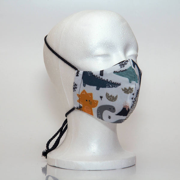 Oltre Print Mask Side View:Blue Dinasaurs print. The soft woven strap is easily adjustable around your head for your comfort. 3 Layer fabric mask with a middle filter layer that is contoured to fit comfortably on your face. Mask will fit pre school boys between 3 to 6 years old.