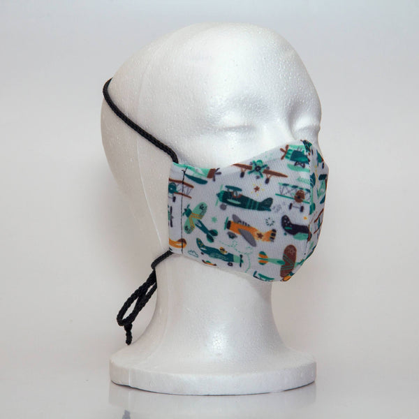 Oltre Print Mask Side View: Planes print. The soft woven strap is easily adjustable around your head for your comfort. 3 Layer fabric mask with a middle filter layer that is contoured to fit comfortably on your face. Mask will fit pre school boys between 3 to 6 years old.